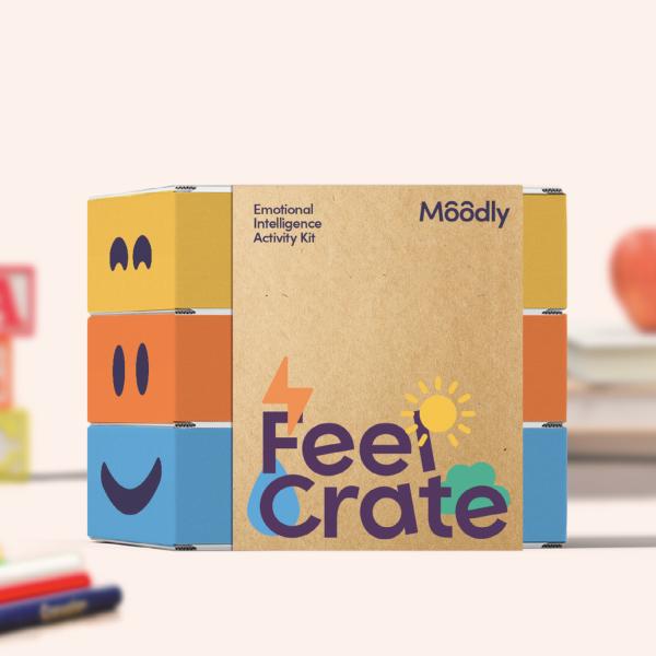 A cardboard package with yellow, orange and blue on the front with a smiling face and the text Feel Crate written on the side.