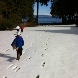 Children running across a snowy lawn