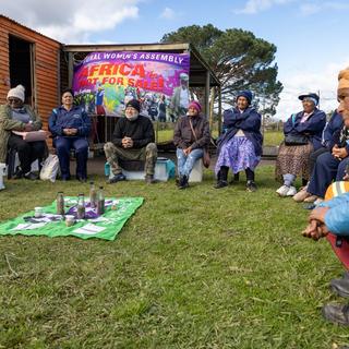 People sit in a circles with a banner behind them that reads Africa is not for sale.