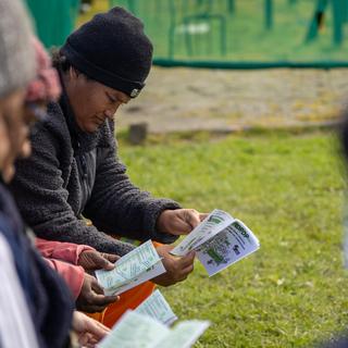 Several people sit in a row reading UNDROP pamphlets.