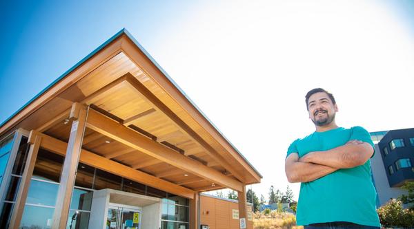 Hayden stands in front of Shq'apthut, VIU's Indigenous gathering place on the Nanaimo campus