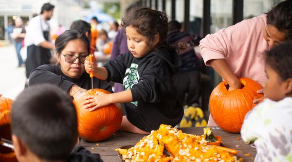 A group of kids carve pumpkins together