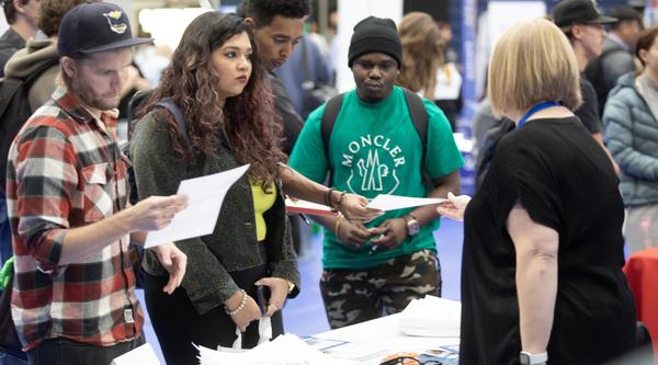 Three students interact with a vendor at the Career Fair