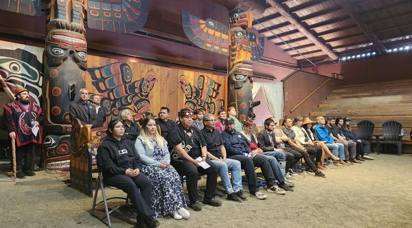 A group of students sits in a longhouse