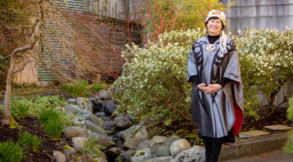 Deborah Saucier wears her convocation regalia and poses in the gardens at VIU's Nanaimo campus