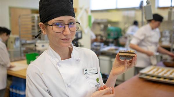 a baking student holds up a Nanaimo bar