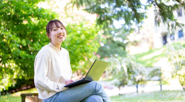 Student working on a laptop in nature