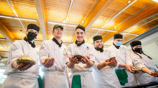 Culinary arts students hold different seafood items