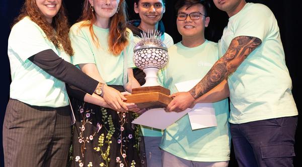 A group of students holds a trophy, all are wearing green shirts