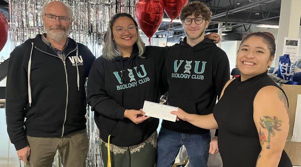 Group of four people holding a cheque
