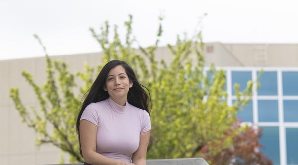 Student sitting on stairs, smiling at camera