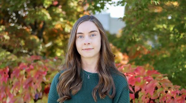 Angelina Jaeger stands in front of a vine covered wall.