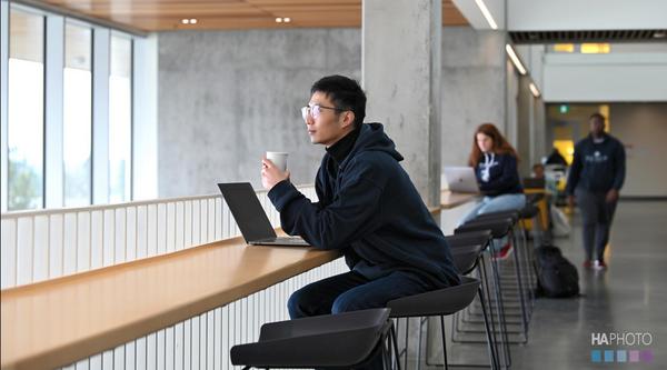 Jiayi Li sitting at a table with a cup of coffee looking out the window