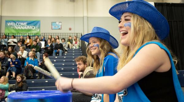 Women wearing blue bang on drums
