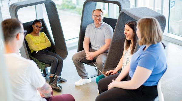 A group of students sits in cool chairs talking with each other