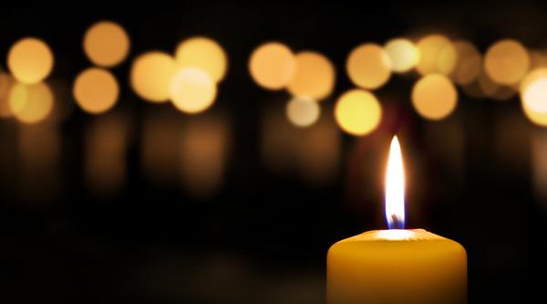 Candle with light of other candles blurred in background