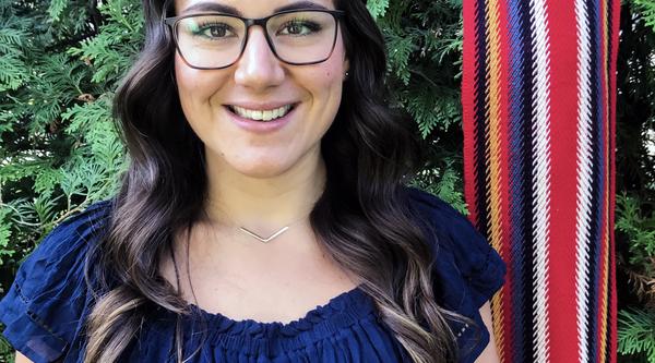 Cassidy Caron smiling with a Metis sash in background