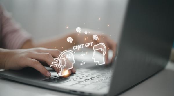 A person typing on a laptop with a graphic of a robot and person with ChatGPT written between them