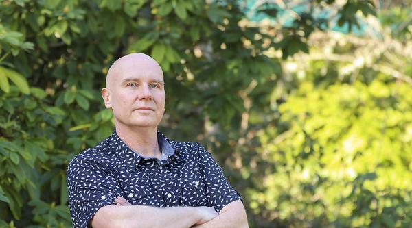 Dr. Chris Gill stands in a forested area at VIU's Nanaimo campus.