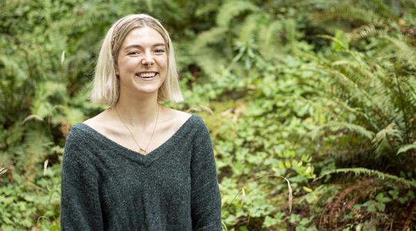 Denman Moody smiles while standing in front of green ferns.