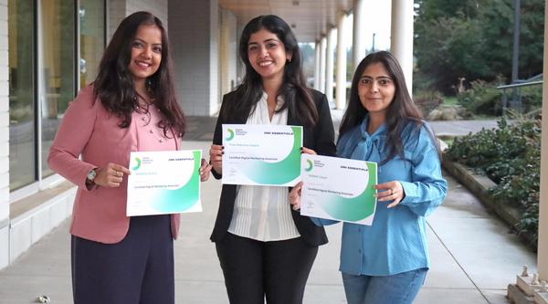 Three women hold certificates