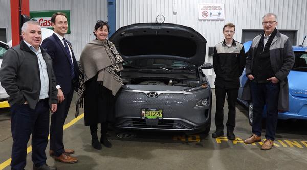 Five people pose around an electric vehicle