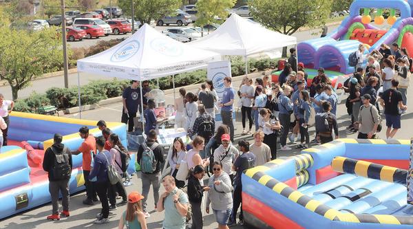 A crowded festival scene with tents and a bouncy castle