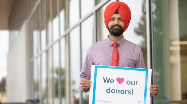Harpreet outside the Centre for Health and Science holding a sign that reads We love our donors! 