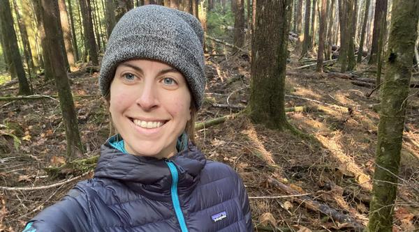 Nadia Linning standing in the woods and smiling at the camera