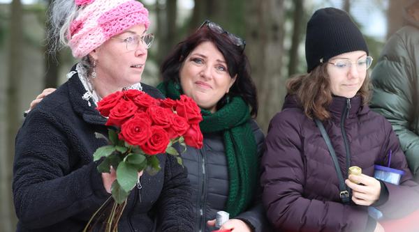 Woman holds roses standing next to two other women