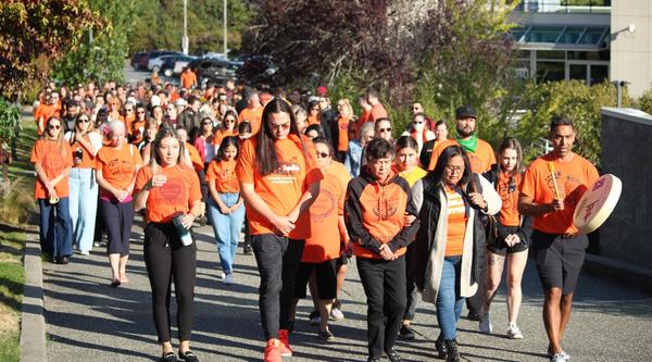 A group of people wearing orange shirts walk together at VIU's Nanaimo campus
