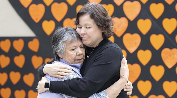 President Saucier and Auntie Geraldine hug in front of a wall of orange hearts