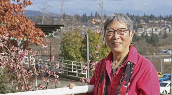 Dr. Imogene Lim stands along a guard rail with the Nanaimo cityscape in the background.