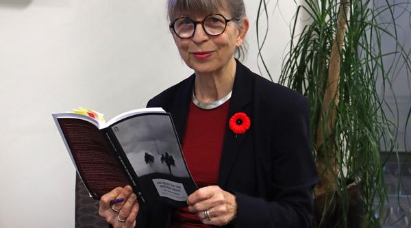 Katharina wears a poppy and holds a copy of her translation of All Quiet on the Western Front