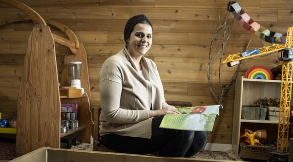 Kholoud sits behind the sandbox in her preschool