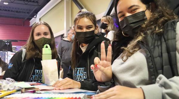 Three students sitting at a table, smiling for camera