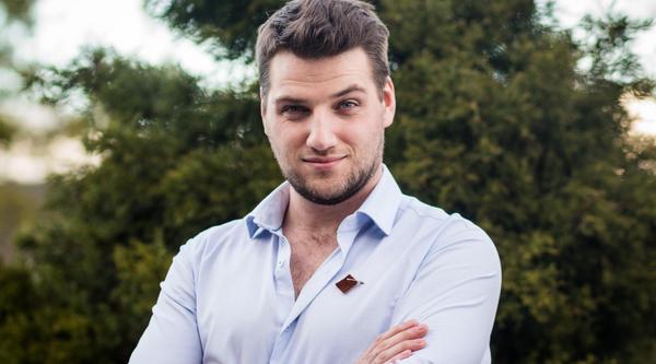 Portrait of Jonah with arms crossed in front of greenery