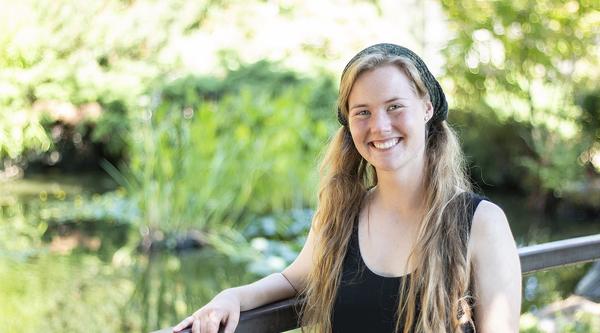 Michaela Medina stands in front of the VIU koi pond, smiling.