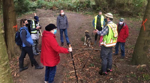 Seven members of the Mid-Island Stewardship Caucus stand in a forest.