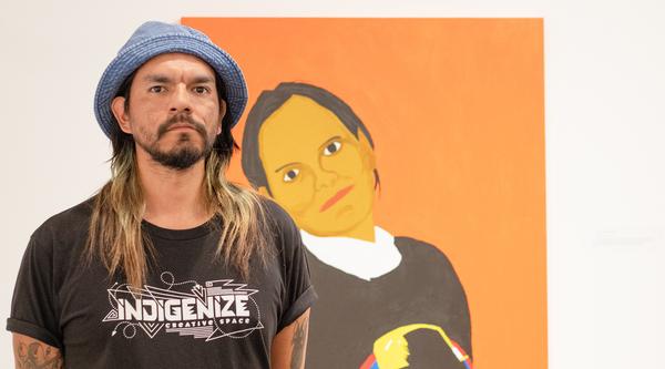 Atticus Mercredi stands in front of the painting of his mother.