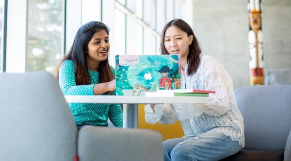 Two women look at a laptop screen together