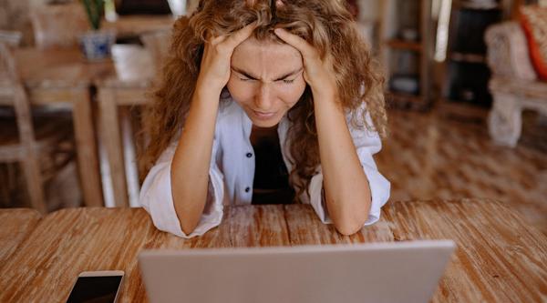 Woman stares at a laptop screen, head in her hands