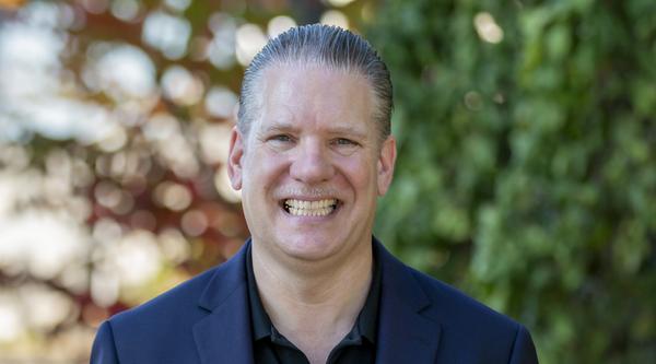 Photo of Dr. Richard Lane, smiling with greenery behind him