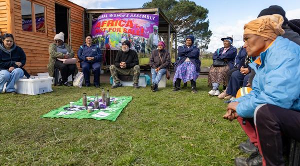 People sit in a circle with a banner behind them that reads Africa is not for sale.