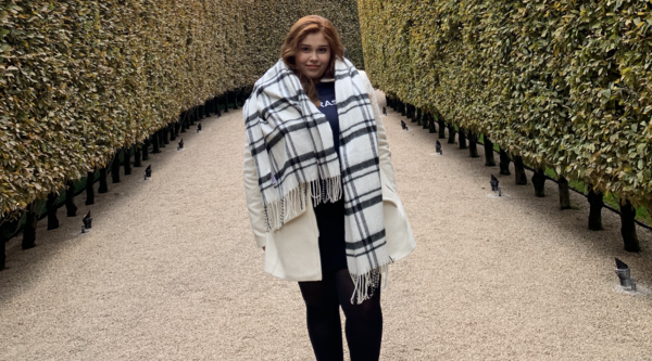 Gabrielle Hayashi Santos standing outside between two hedges looking at the camera 