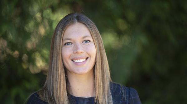Dr. Serene Kerpan standing outside against a backdrop of greenery and smiling at the camera.