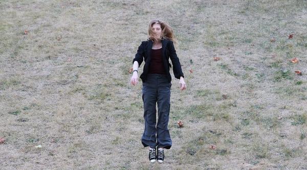 Samantha jumping in a field of scraggly grass