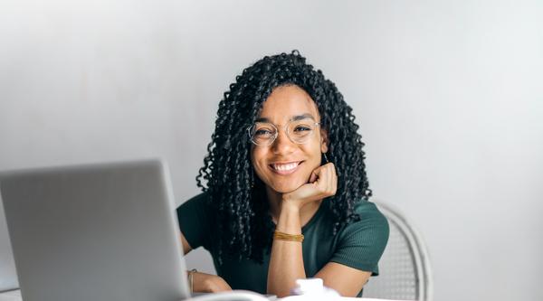 Girl looking up from laptop and smiling at the camera