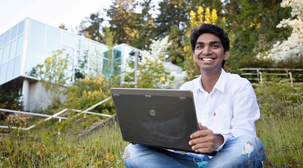 Student typing on laptop outside