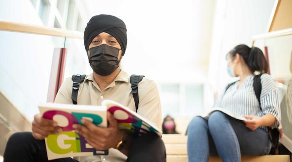 Student sitting on stairs with book